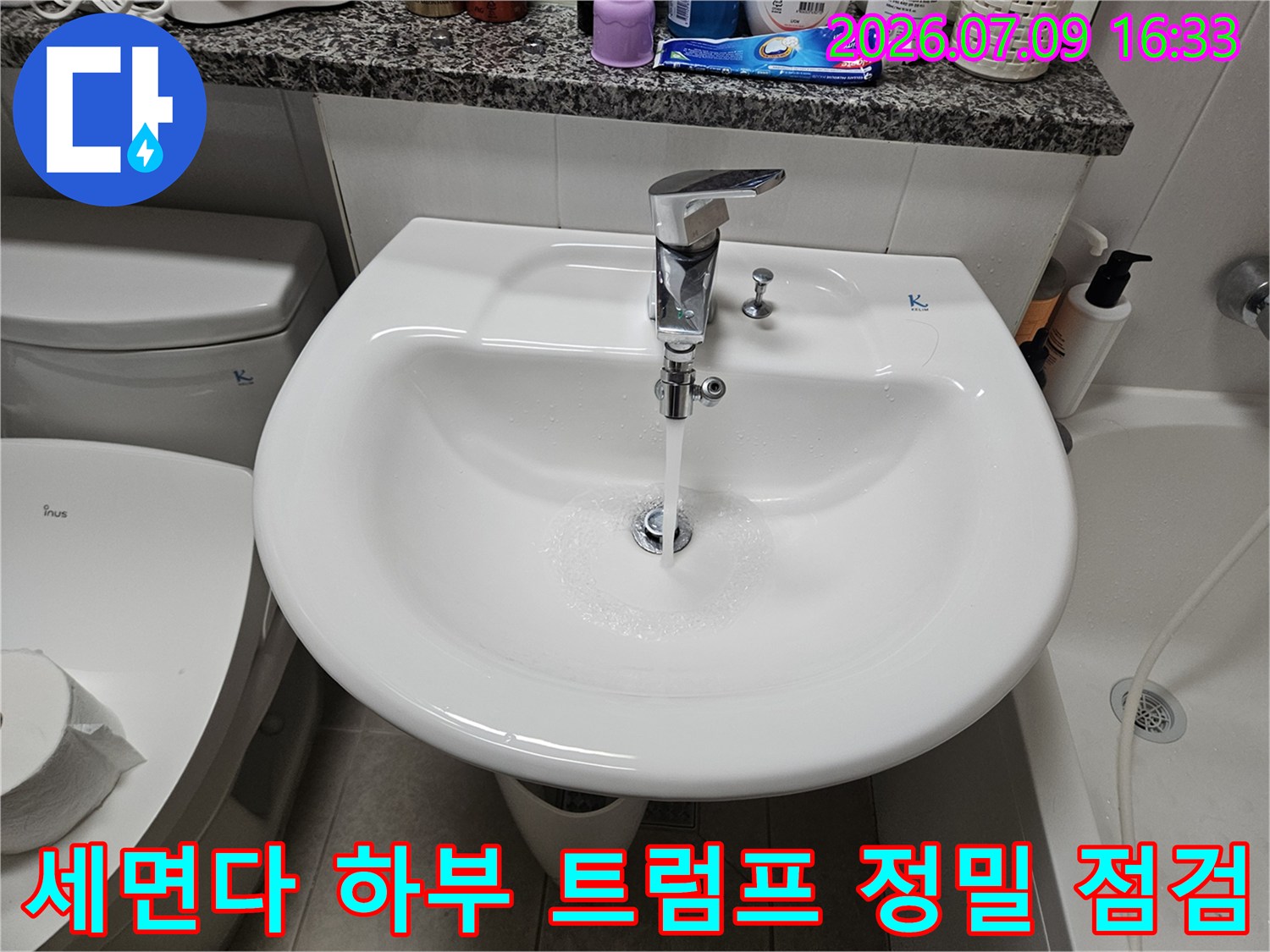 세면대 아래 위치한 금속 재질의 배수 장치와 호스 연결 상태를 세밀하게 살피는 모습