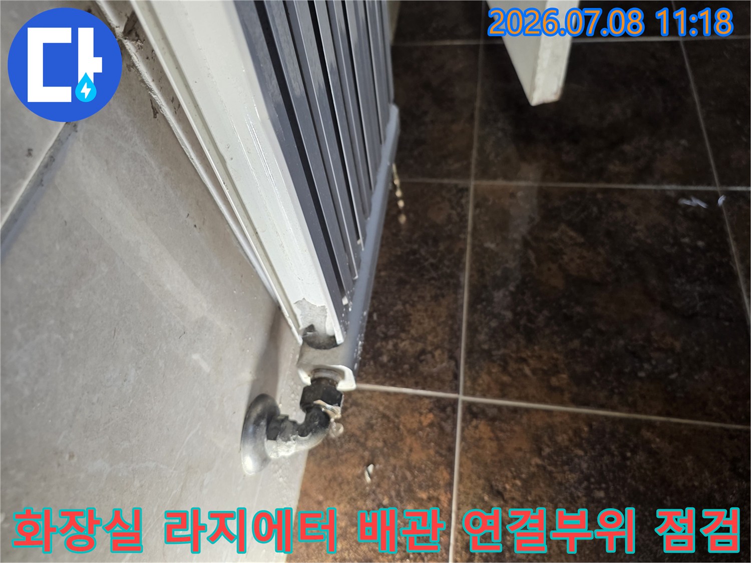 화장실 바닥에 설치된 라지에터와 연결된 배관 부위의 누수 점검 모습