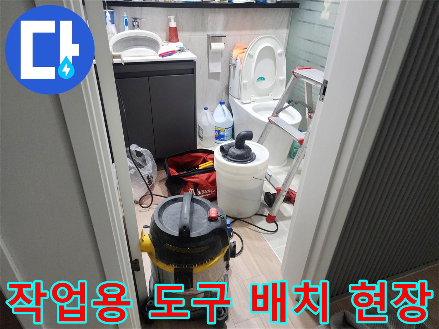 욕실 세면대 아래 놓인 청소기와 작업 도구들