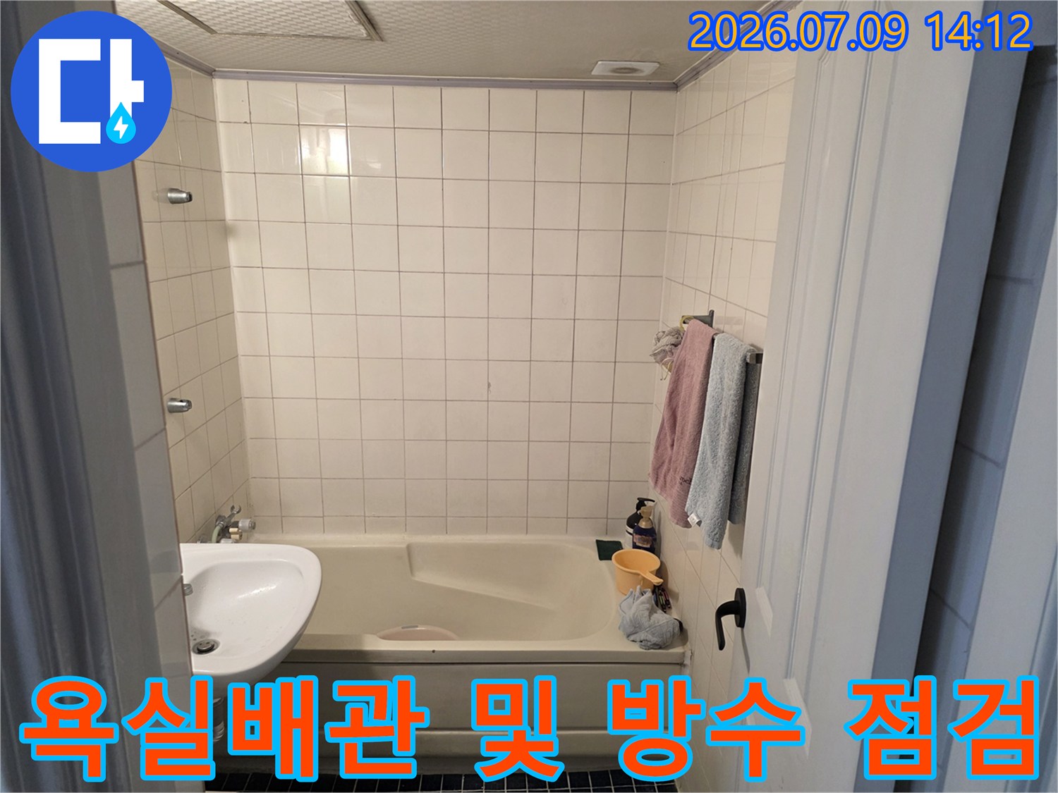 하얀색 타일로 마감된 욕실 내부의 세면대와 욕조 구조물