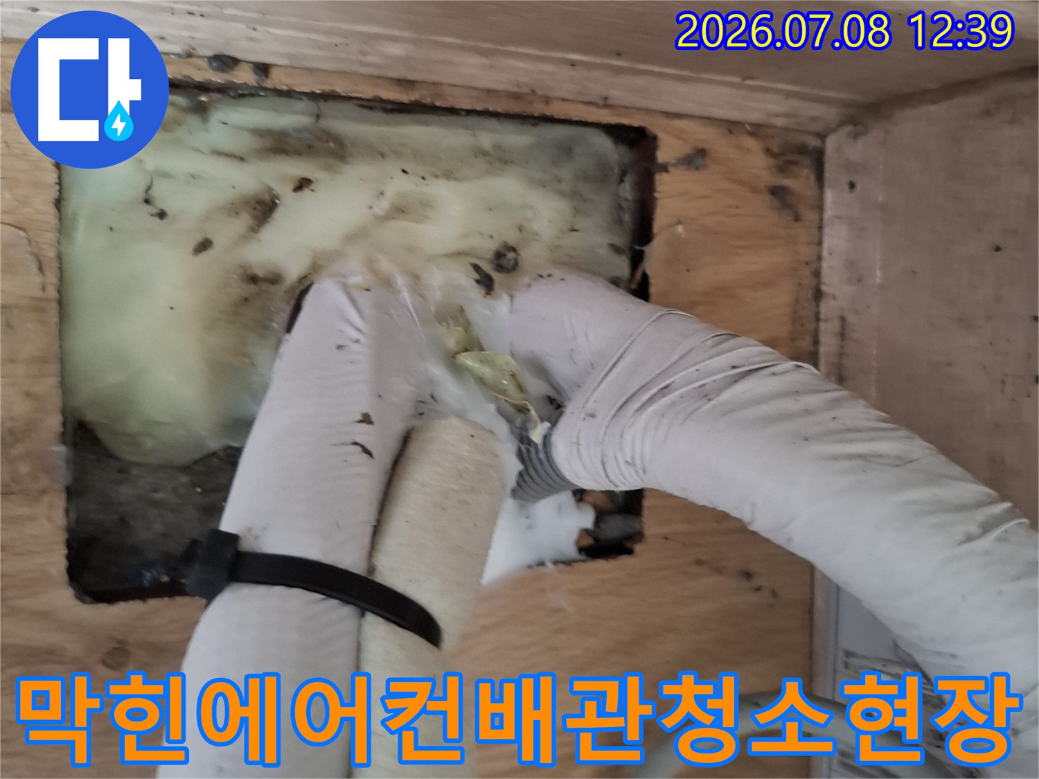 작업자가 장갑을 착용하고 매립된 에어컨 배수 라인을 세척하는 모습