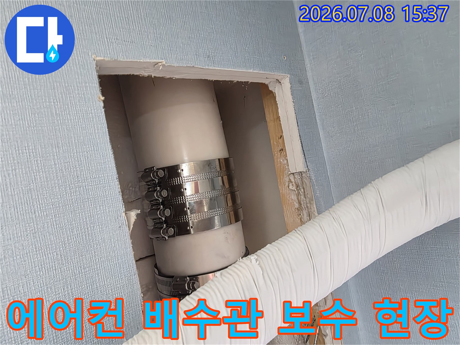 금속 밴드로 고정된 에어컨 배수관의 벽면 절개 점검 부위