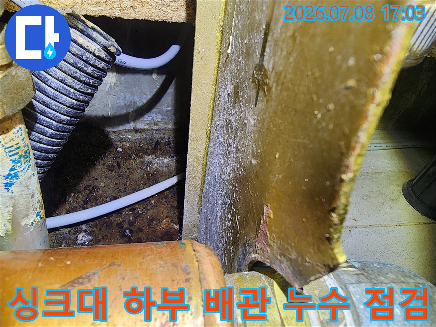 싱크대 아래쪽 배관 연결 부위와 주변에 발생한 습기 및 오염 흔적을 조사하는 모습