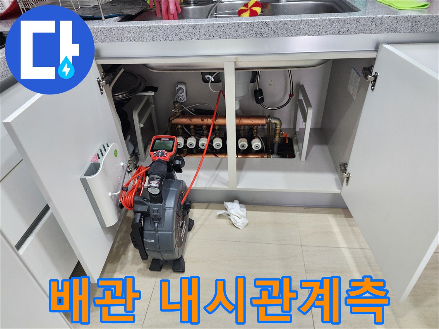 싱크대 하부장 내부 배관과 내시경 모니터 장비의 배치 상태