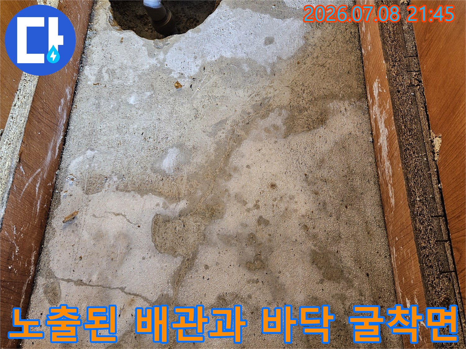 먼지 묻은 콘크리트 바닥에 노출된 파란색 및 회색 배관의 모습