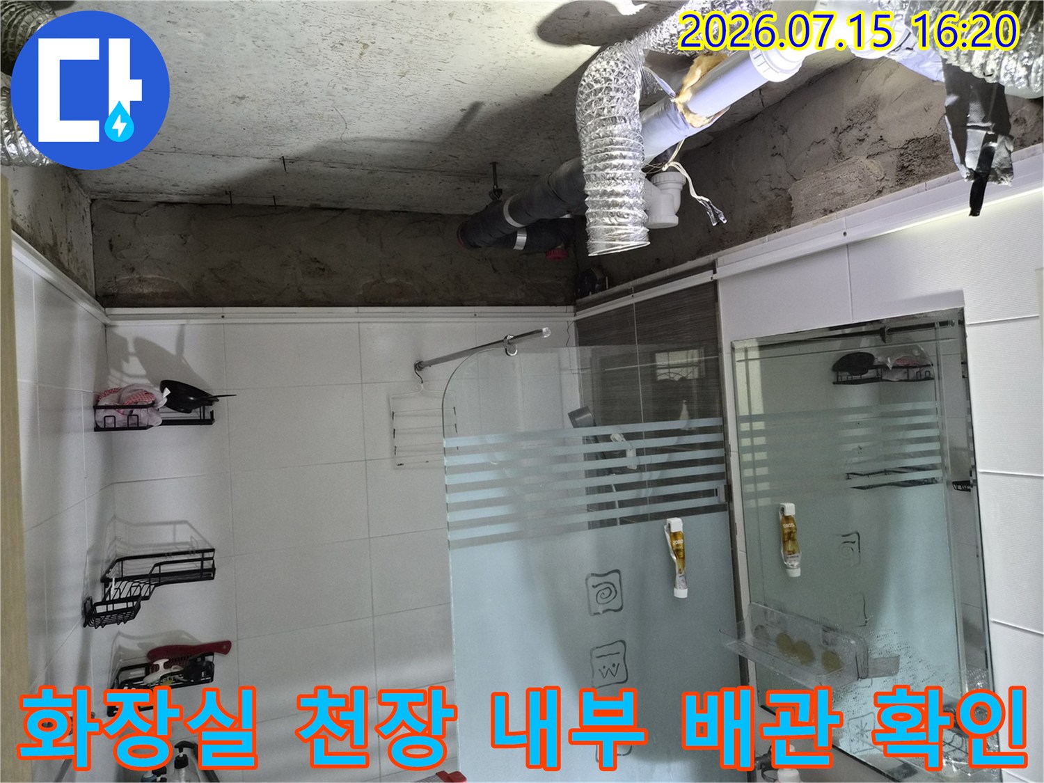 노출된 화장실 천장 내 배관과 환기 덕트 및 조명 설비 점검 모습