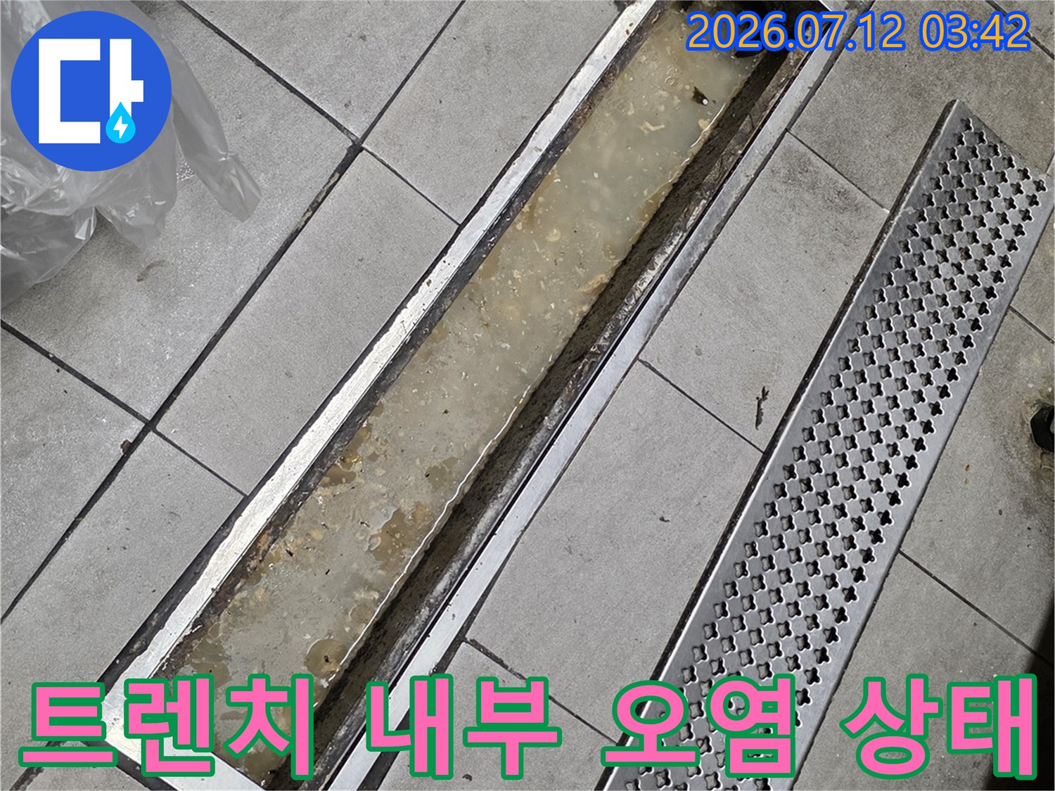 이물질과 흙이 쌓인 트렌치 배수구 안쪽을 촬영한 사진입니다.