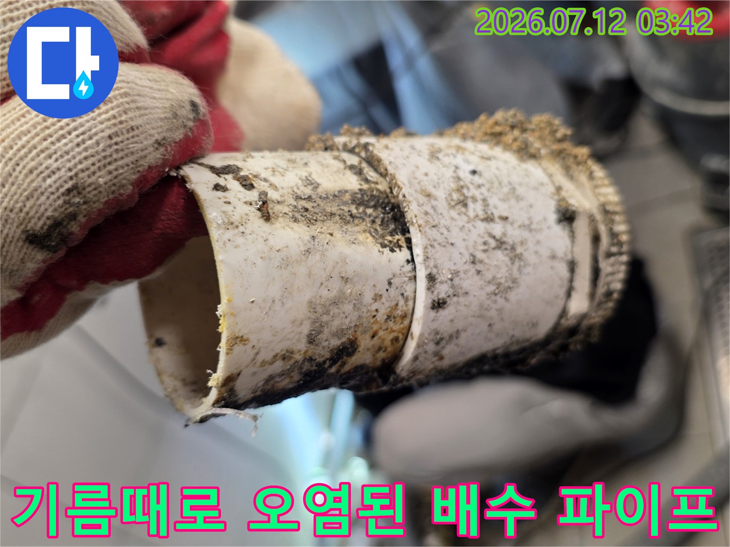 장갑 낀 손으로 들고 있는 기름 찌꺼기가 가득한 노후된 하수관