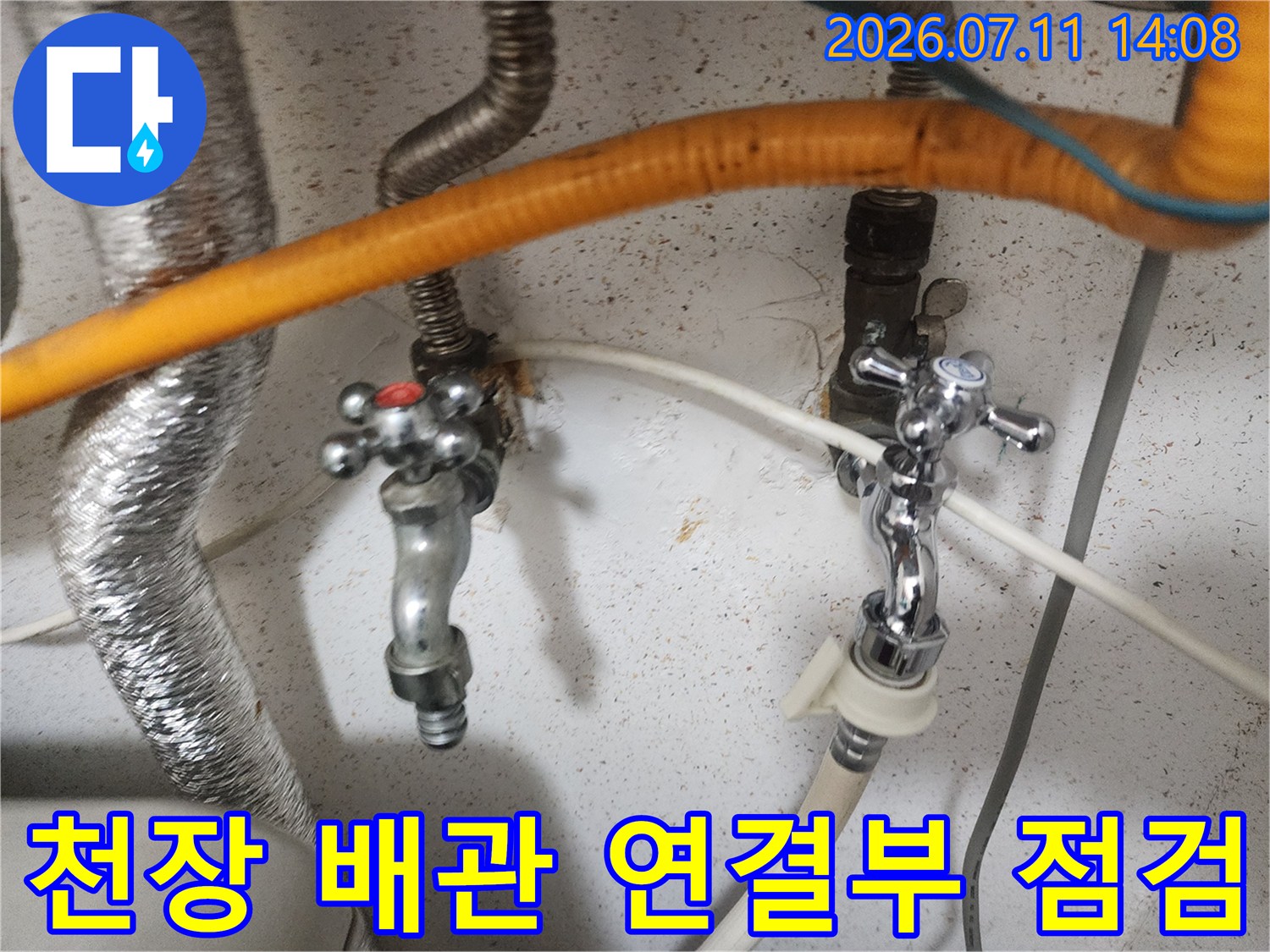 화이트톤 벽면과 은색 금속 배관 및 주황색 보온재가 노출된 천장 내부 모습