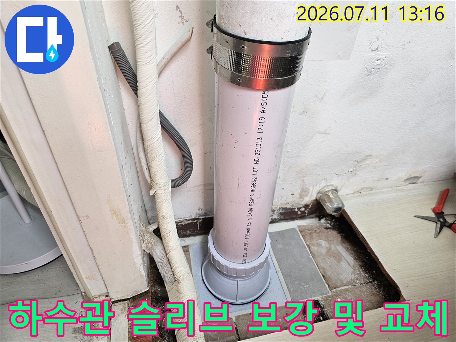 흰색 배관을 고정하는 금속 밴드와 수직으로 연결된 배관 구조물
