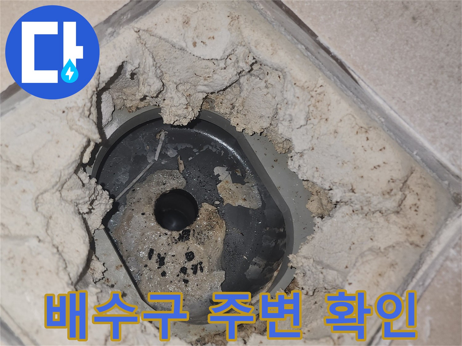 배수구 주변의 깨진 타일과 노출된 바닥 면 상태