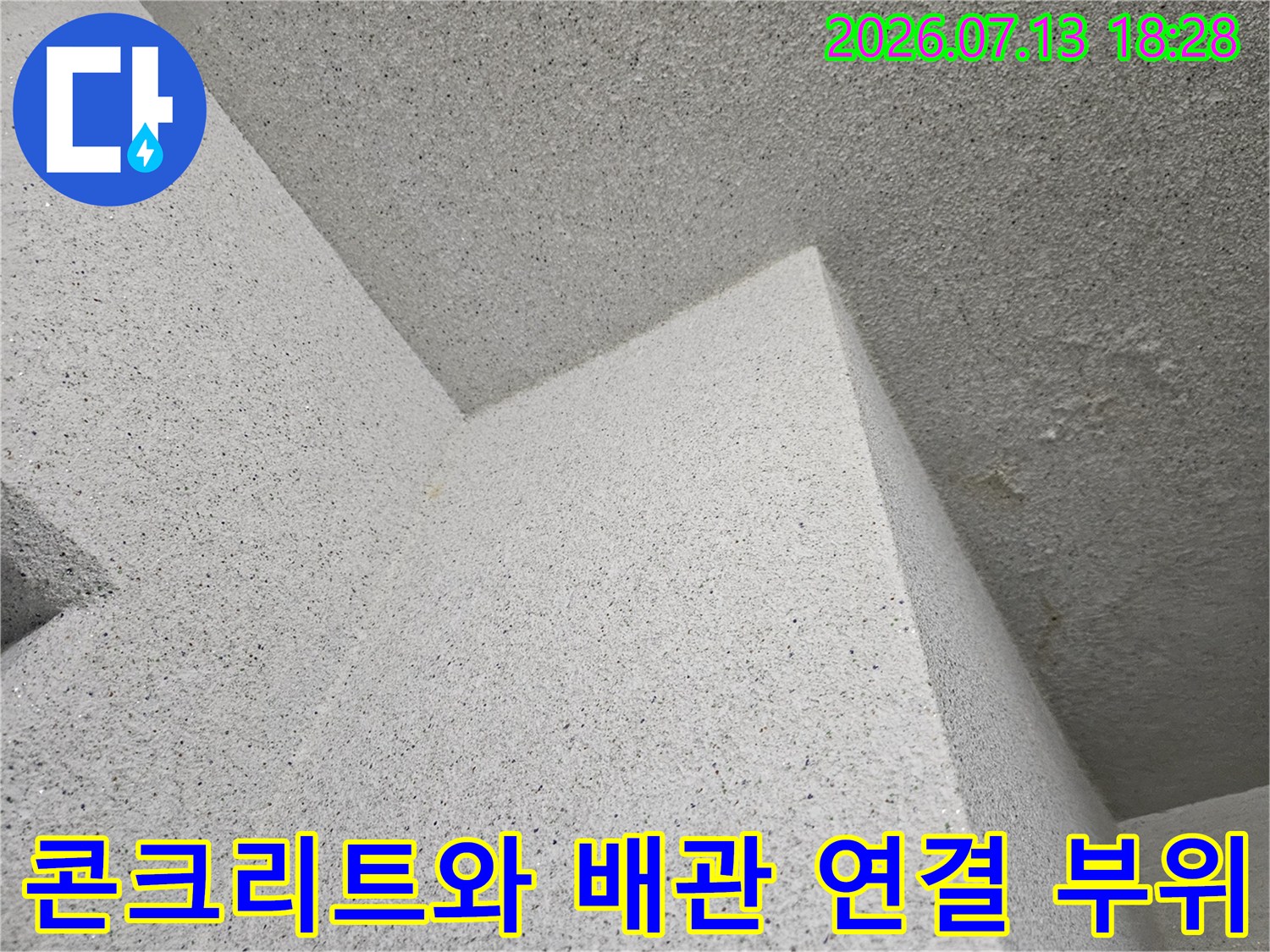 거친 콘크리트 표면과 노출된 배관의 접합부 모습
