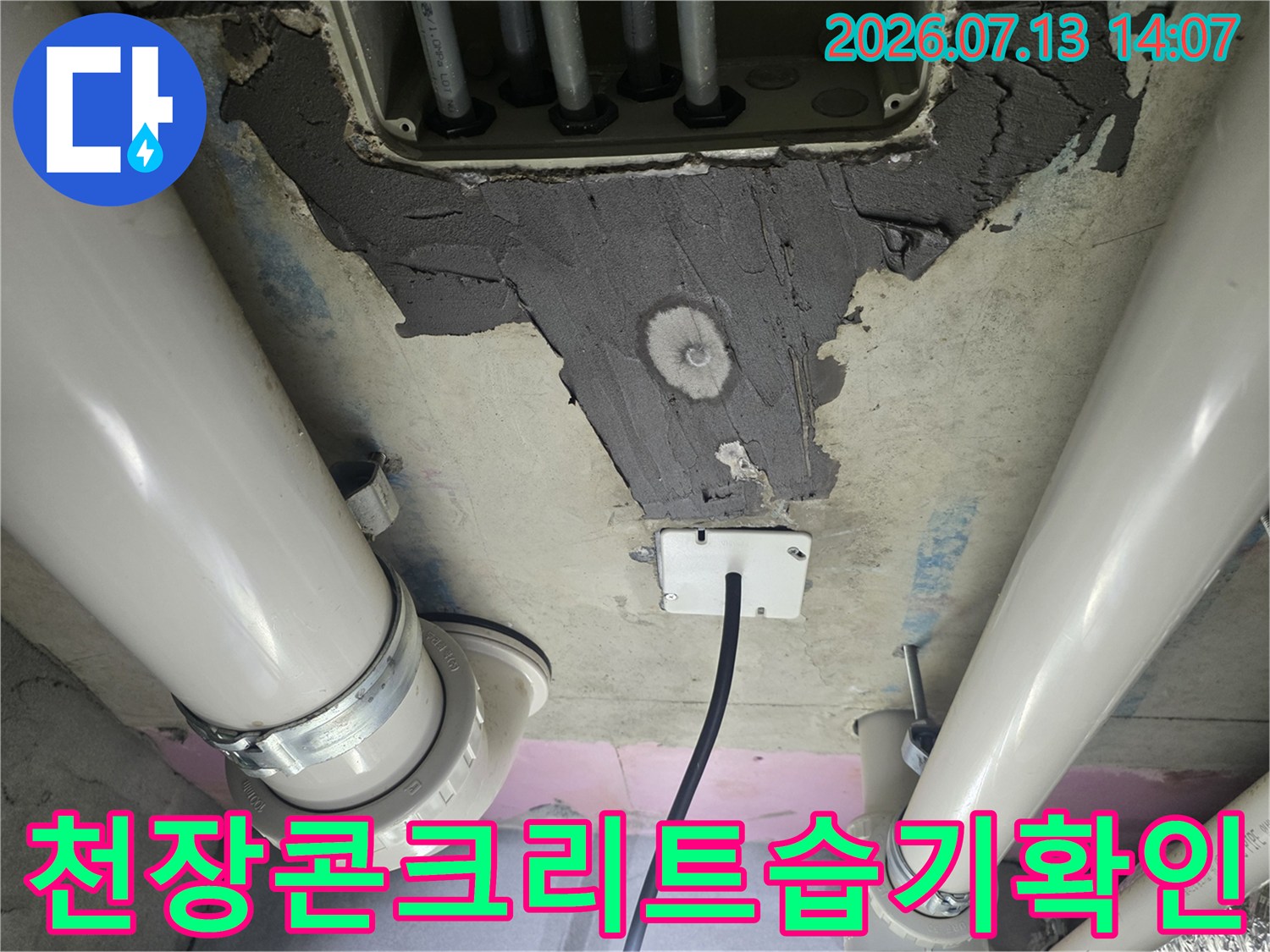 젖은 콘크리트 벽면과 배관이 연결된 화장실 천장 내부 모습