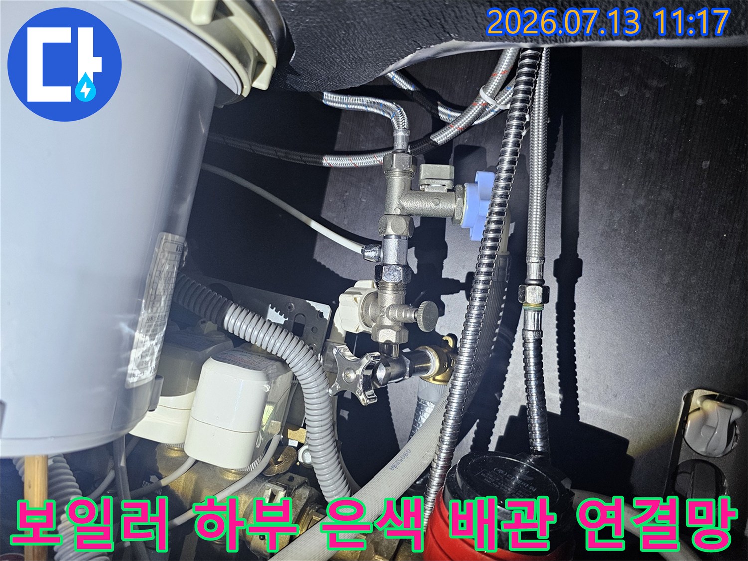 은색 금속 관들과 파란색 밸브가 복잡하게 얽혀 있는 보일러-하단모습