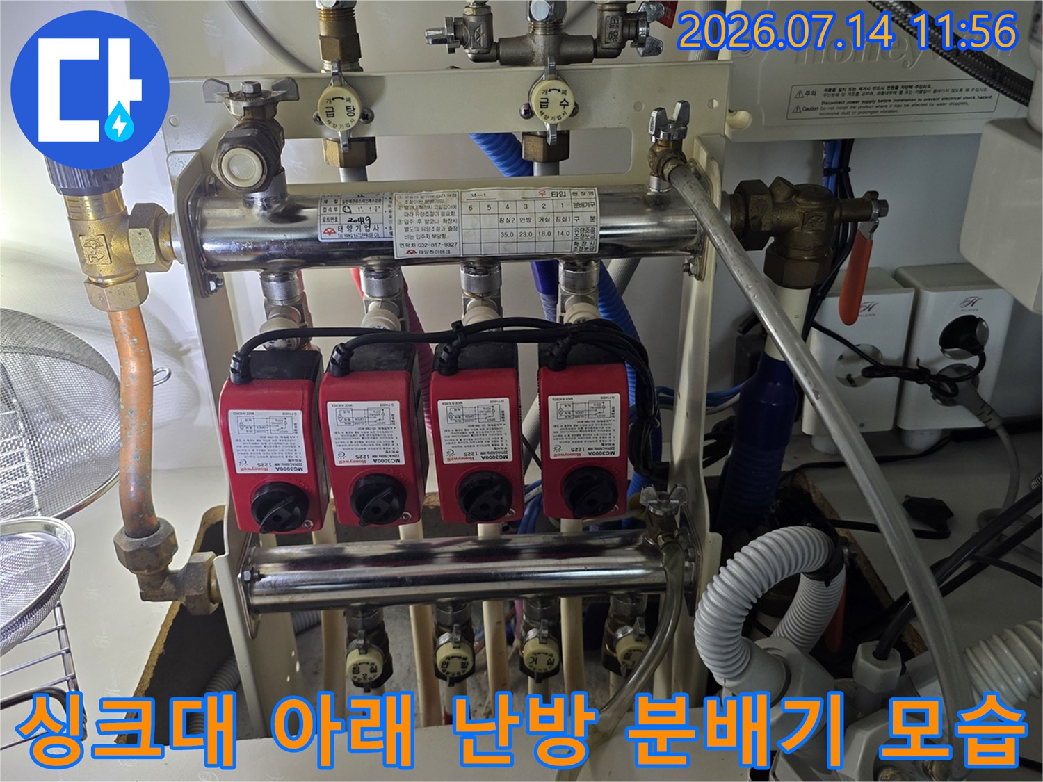 좁은 공간에 설치된-금속제 난방 분배기와-빨간색 조절 밸브 장치