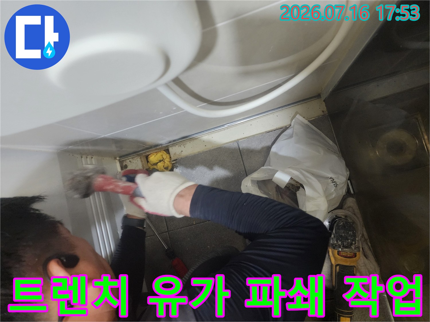 작업자가 장갑을 끼고 전동공구로 트렌치 유가를 제거하는 모습