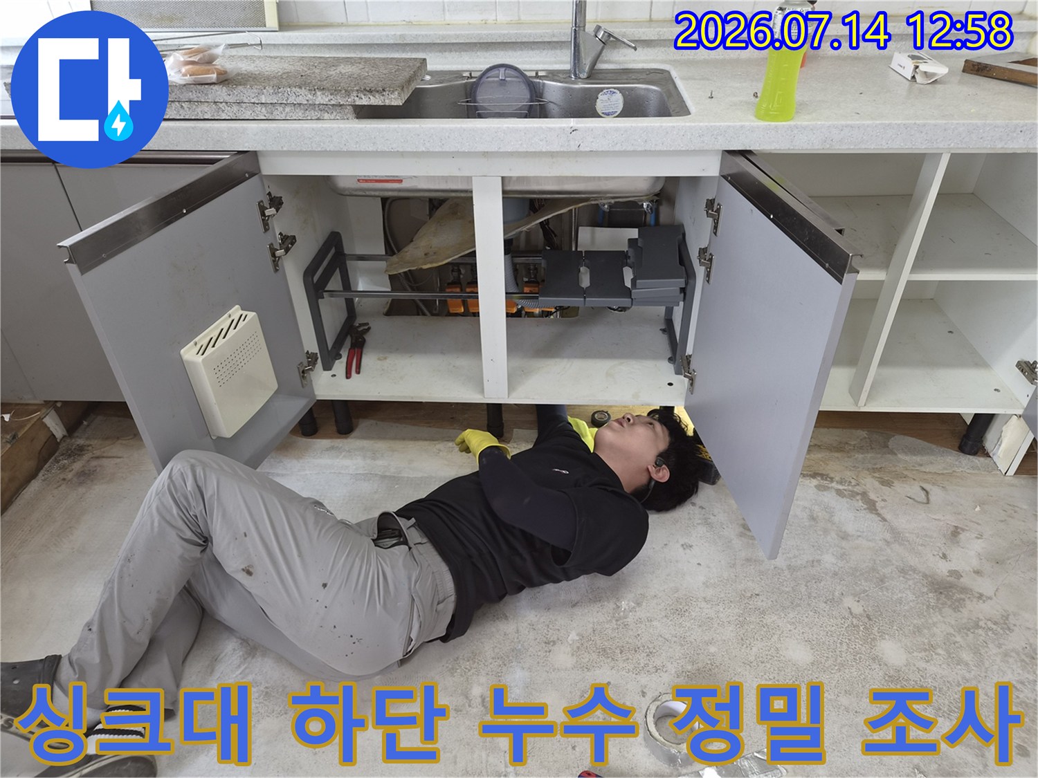 작업자가 싱크대 아래 좁은 공간에서-배관 연결 부위의 이상 유무를 점검하는 장면