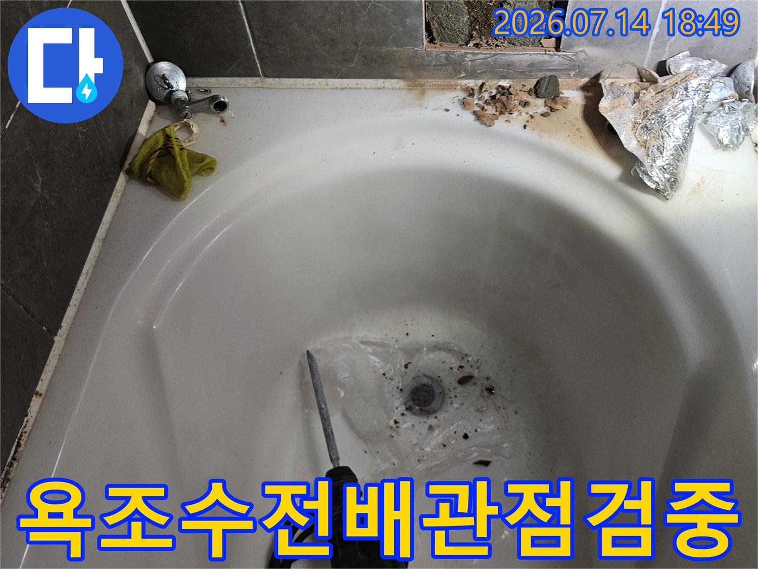 욕조 수전 부위의 타일을 제거하고 전동 공구로 배관을 점검하는 모습