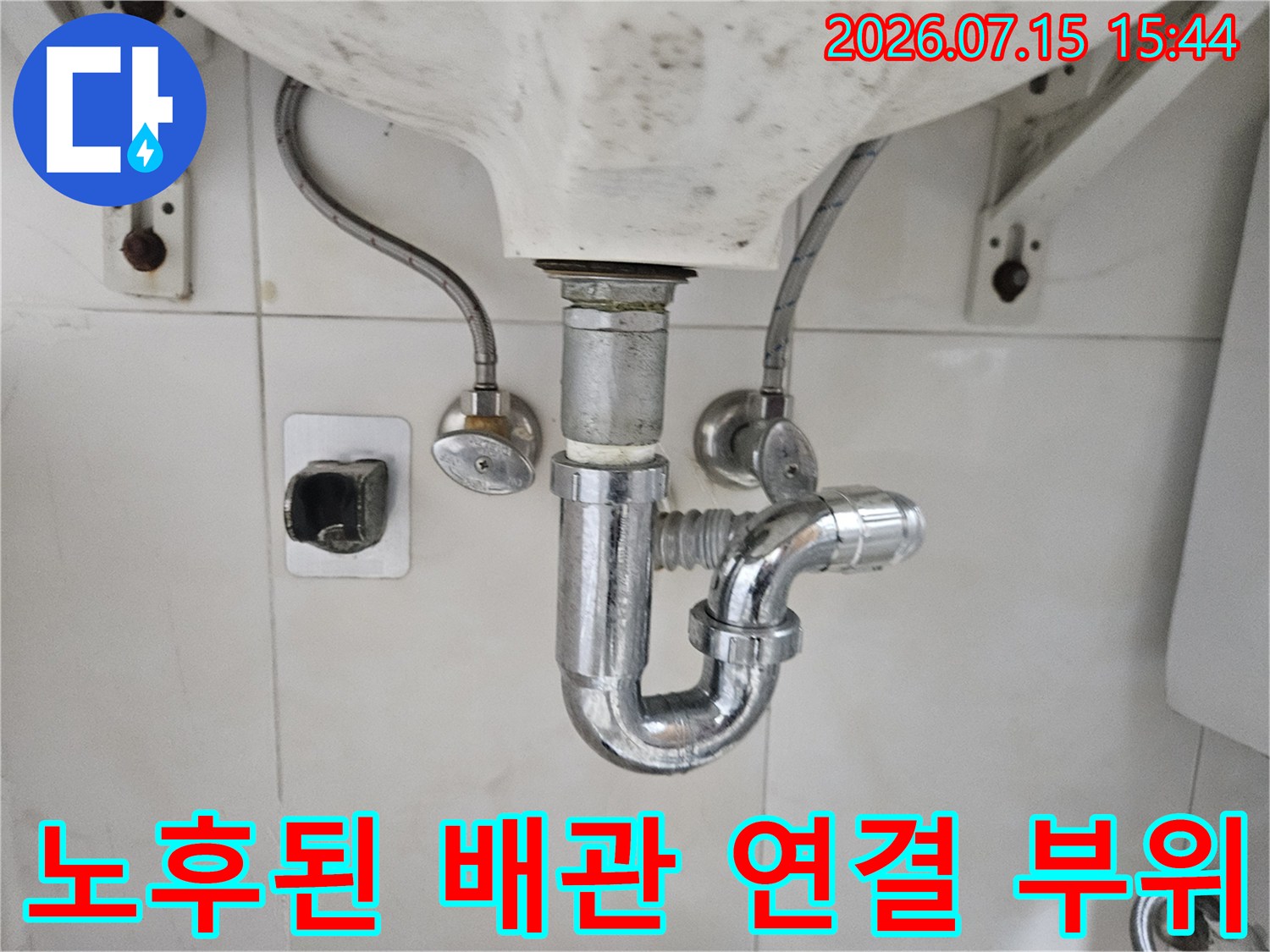 세면대 아래 노출된 배관 트랩과 벽체 연결부의 상세 촬영