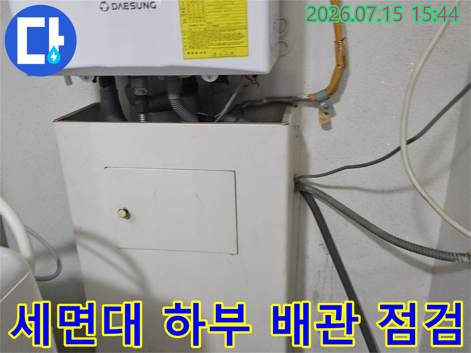 화장실 세면대 밑부분의 노출된 수전 및 배관 구조를 촬영한 사진