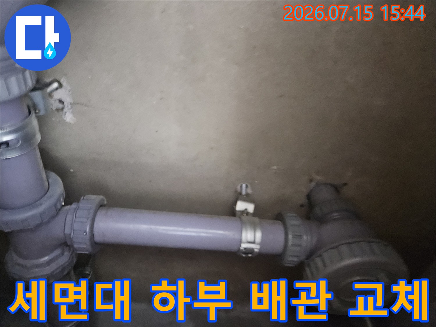 회색 배관이 연결된 세면대 하부 구조물과 노후 배관 보수 현장