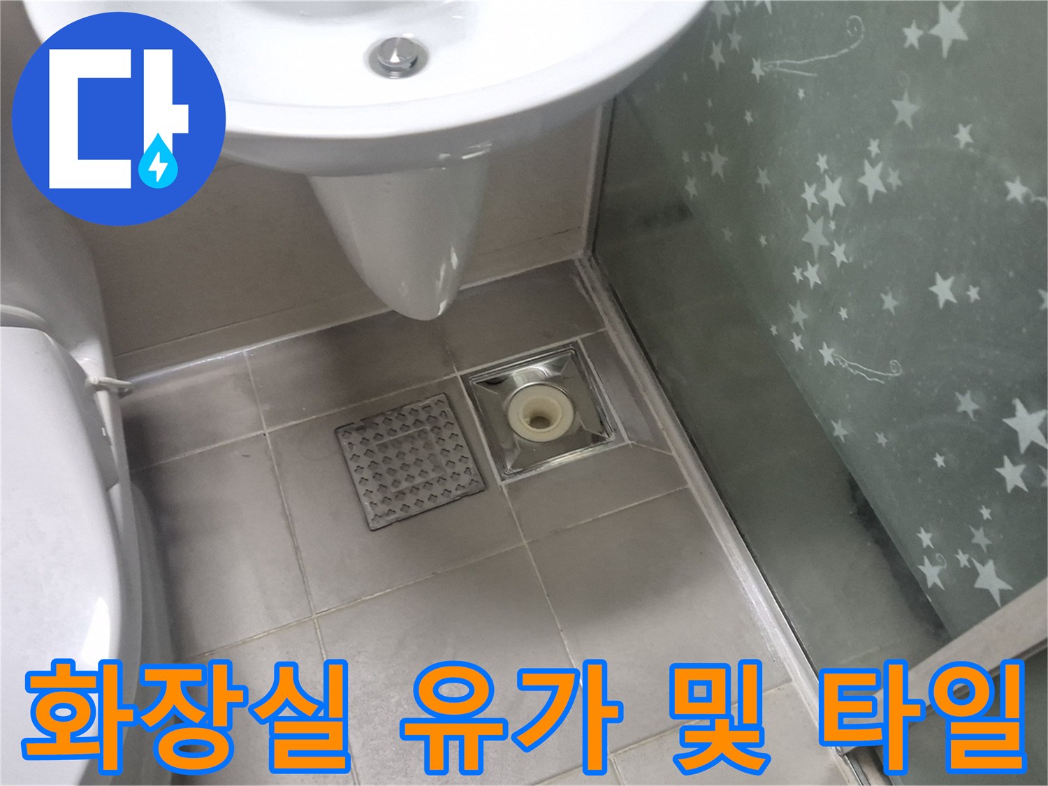 세면대 아래 위치한 배수 트랩과 바닥 타일의 근접 사진
