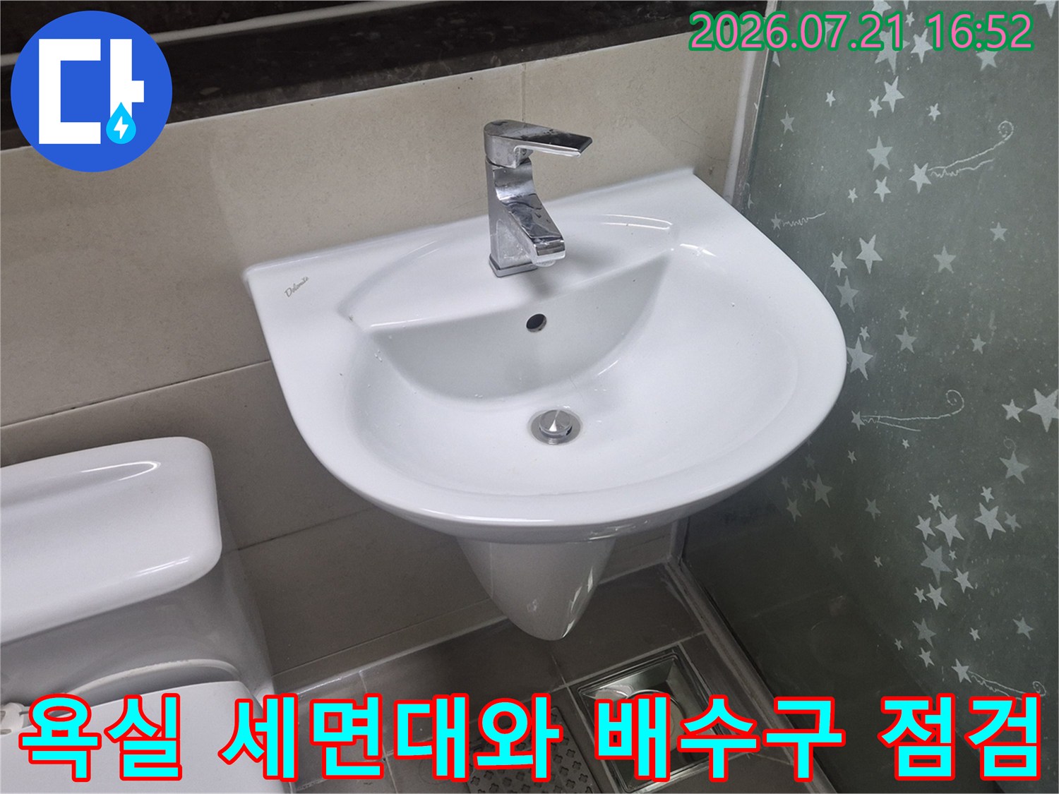 하얀색 세면대가 설치된 욕실과 그 아래 노출된 배수구 파이프 모습