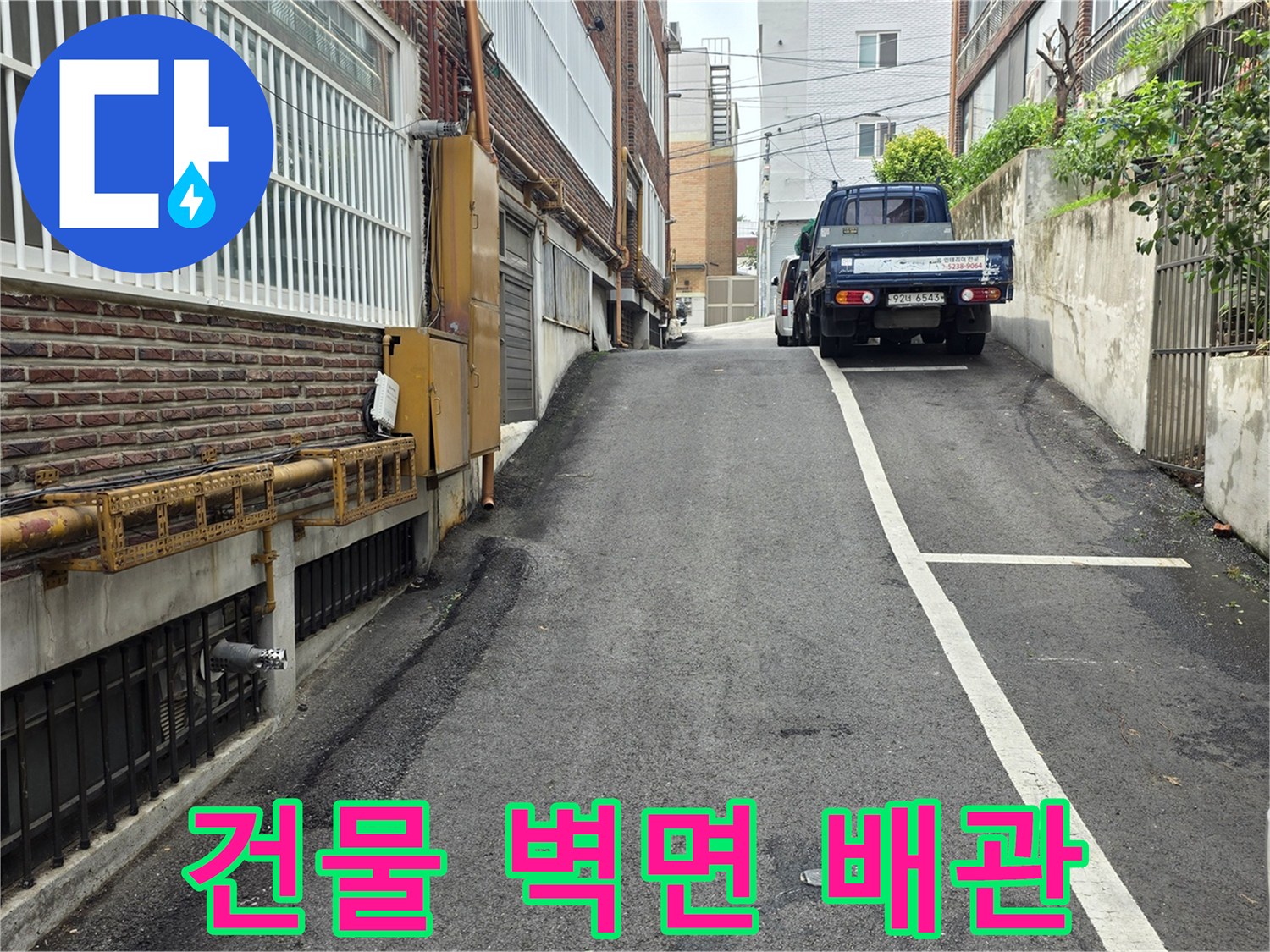 건물 사이 통로의 배관과 아스팔트 지면 촬영