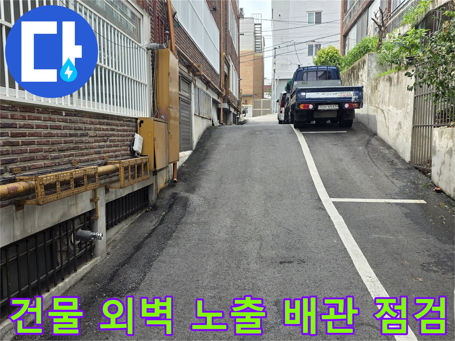 아스팔트 도로와 맞닿은 건물의 노출된 급수 및 배수 배관