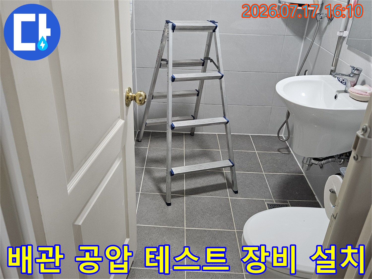 화장실 천장 내부에서 배관 압력 검사를 위해 연결된 게이지와 호스