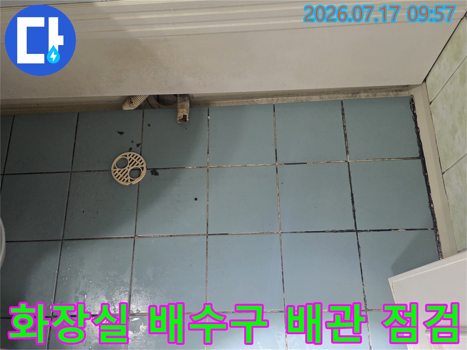 화장실 바닥 타일 위 노출된 배수용 유가와 파손된 배관 연결 부위