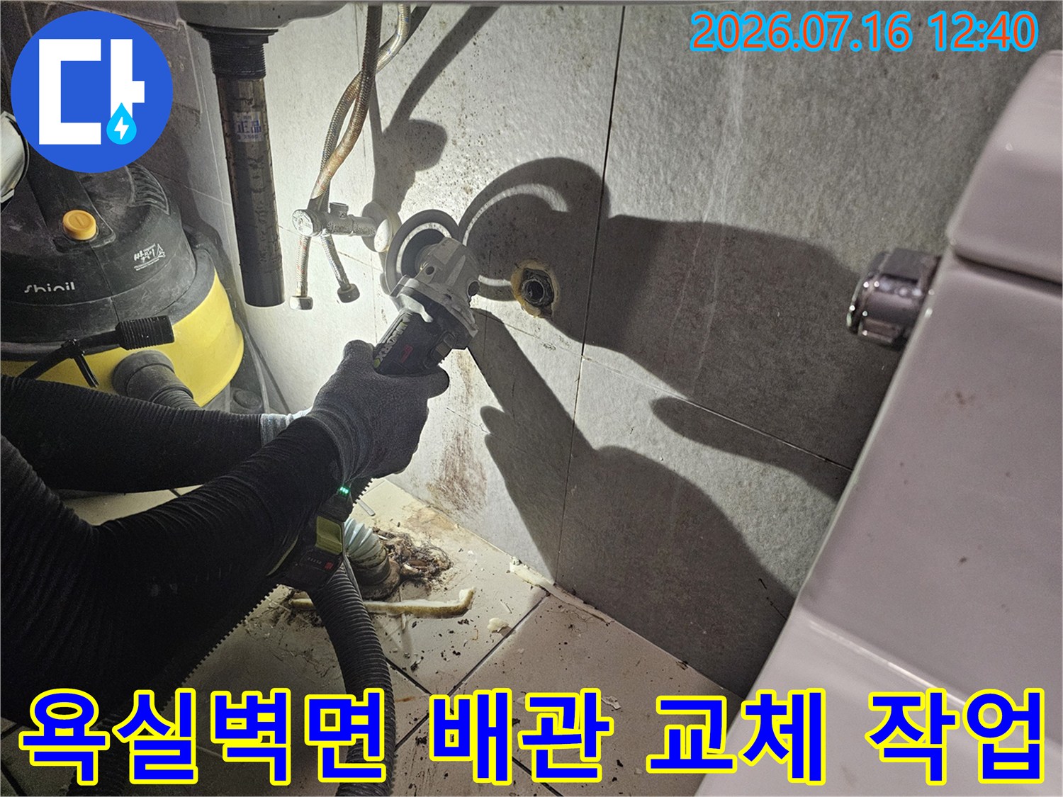 작업자가 욕실 벽면 타일을 굴착하고 노출된 배관 부위를 점검하는 모습