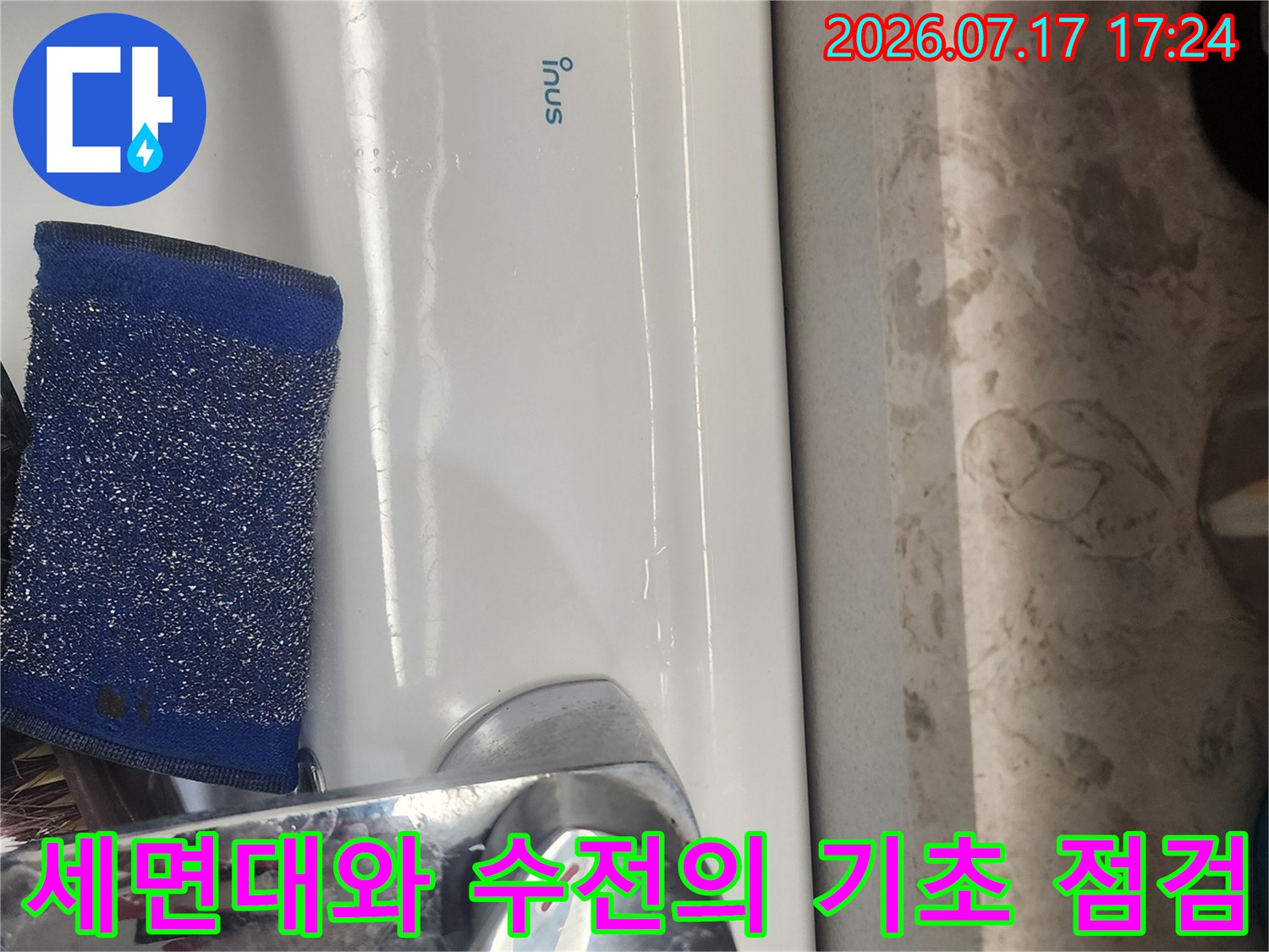 흰색 세면대에 위치한 파란색 스펀지와 은색 수도꼭지 구조물