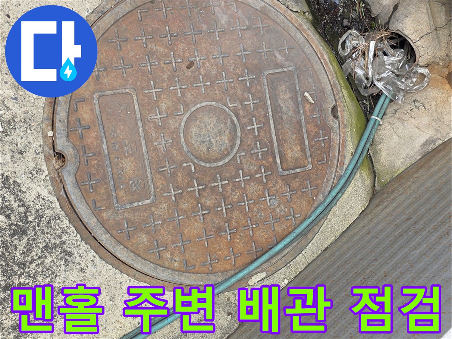 점검용 호스가 연결된 맨홀 뚜껑과 주변 바닥 상태