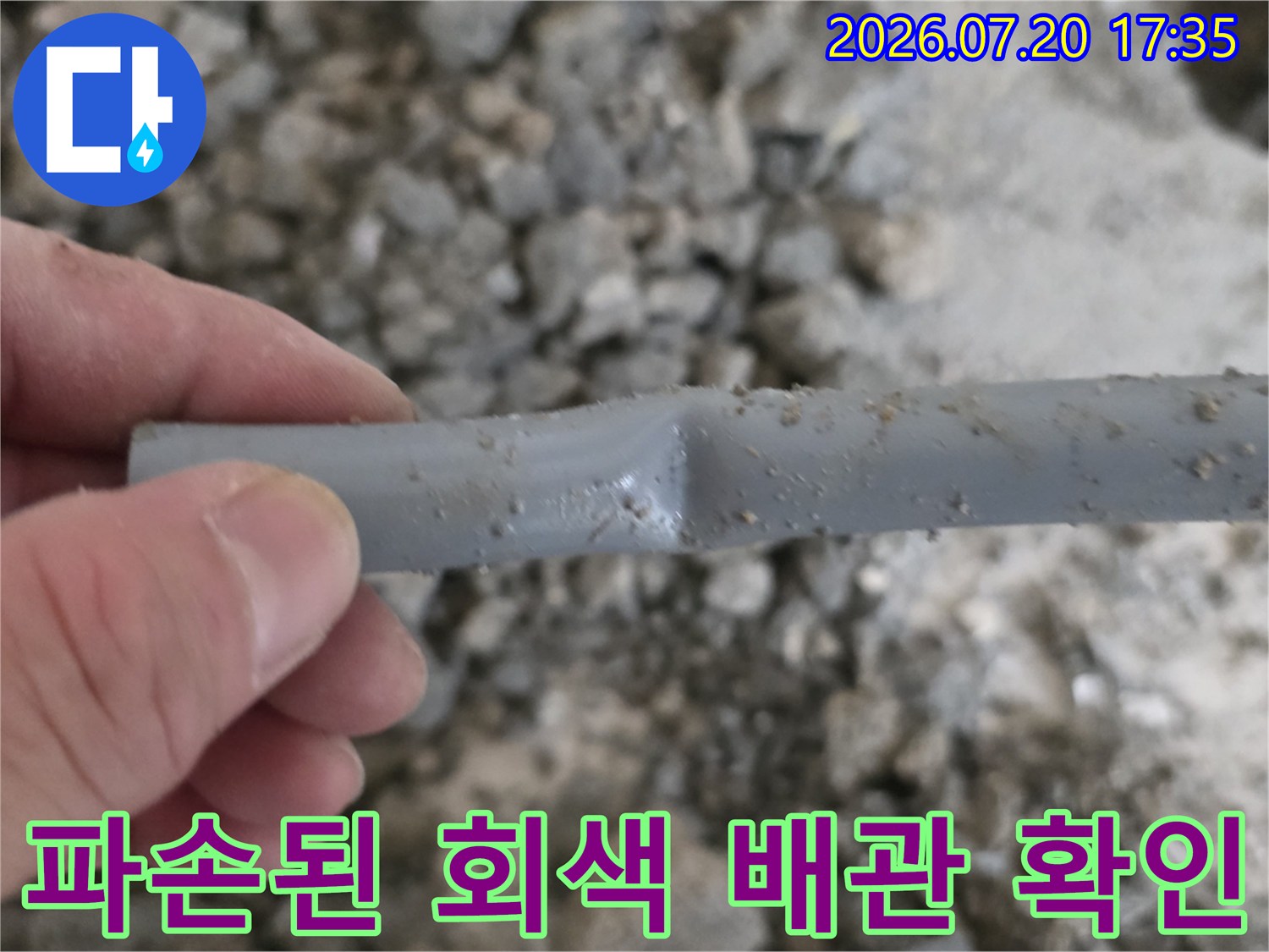 파손되어 절단된 회색 배관의 단면을 손으로 들어 올린 모습