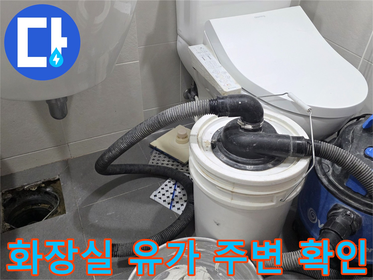 변기 옆 타일 바닥의 노출된 하수구와 청소용품