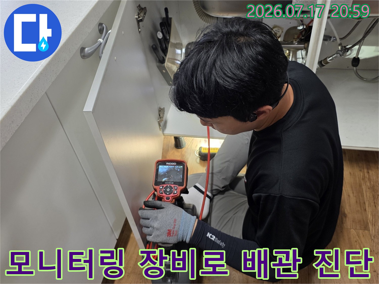 작업자가 단말기 화면을 보며 싱크대 하부의 배수관 상태를 정밀하게 분석함