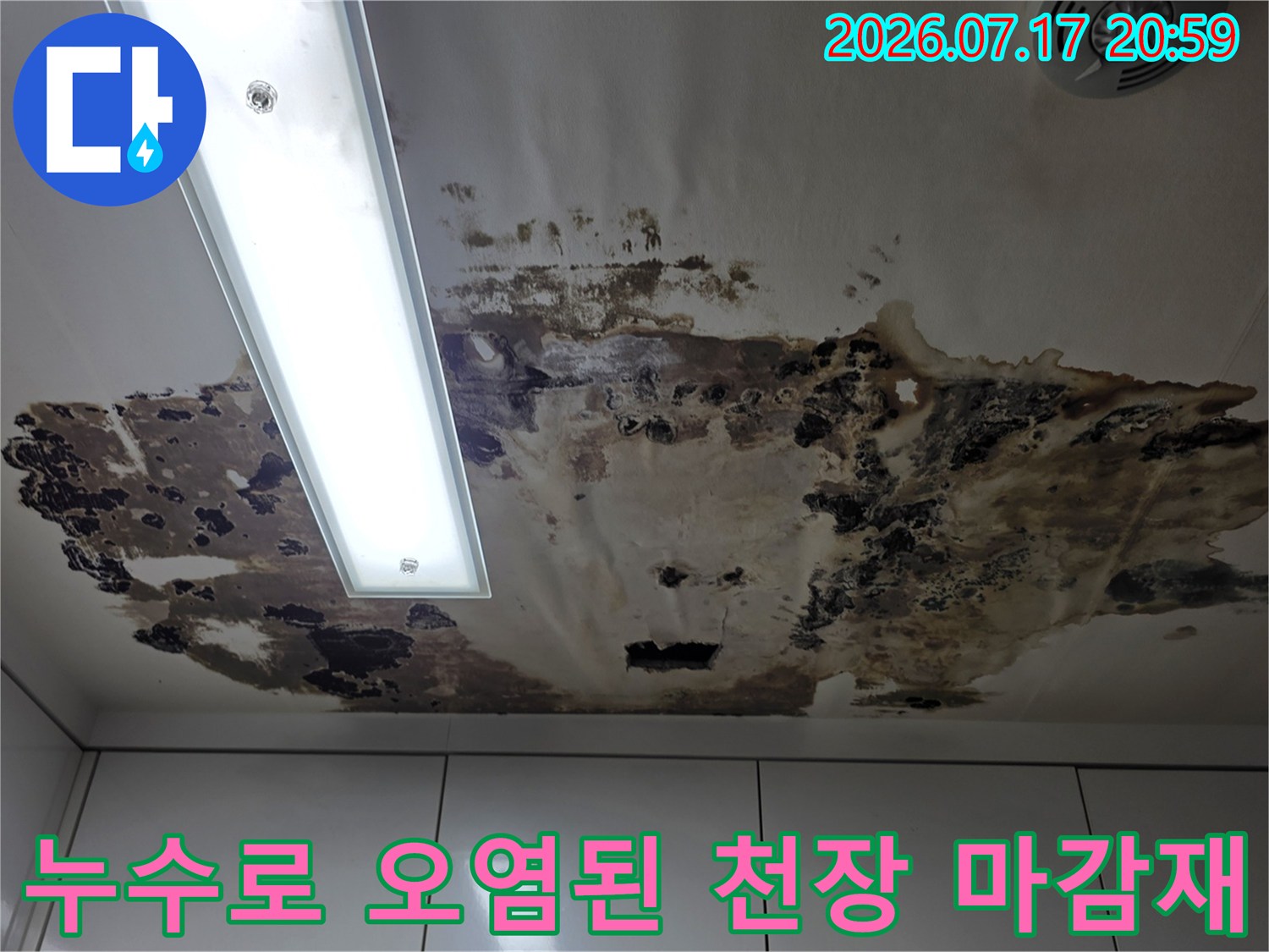 화면 중앙에 조명 기구가 있고 주변이 누수로 변색된 상태의 천장