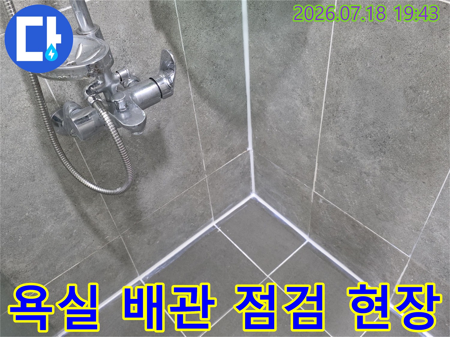회색 타일과 수전이 설치된 욕실 내부의 배관 연결 부위 모습