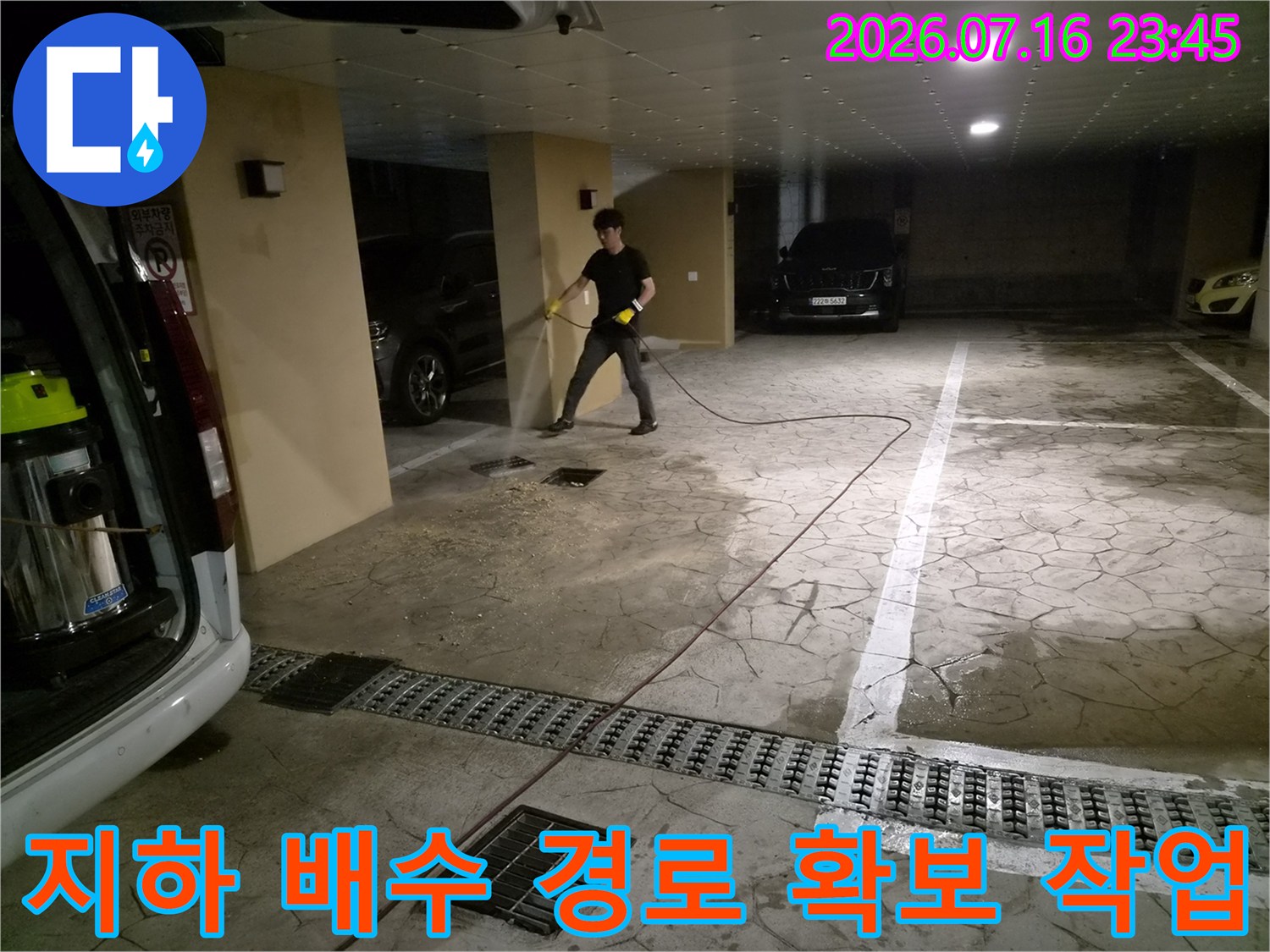 고압 세척기 호스를 연결하여 지하 주차장 공용 배수구 내부를 청소하는 과정