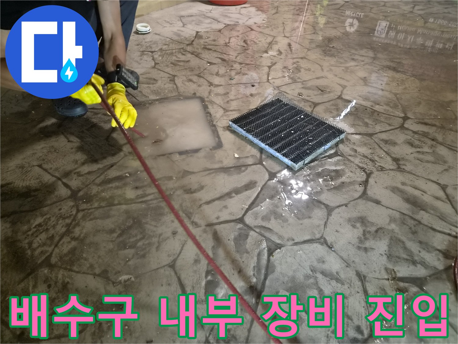 하수구 막힘 제거를 위해-격자 모양 배수 덮개 아래로 장비를 넣는 장면