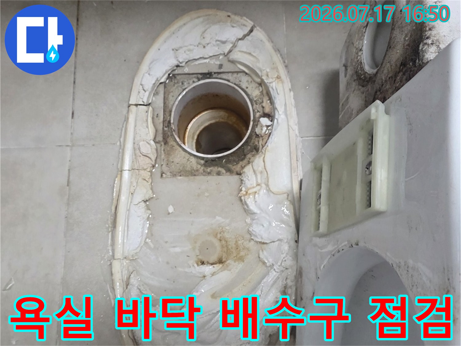 변기 옆 노출된 배수관 주변의 백화 현상과 타일 파손 부위