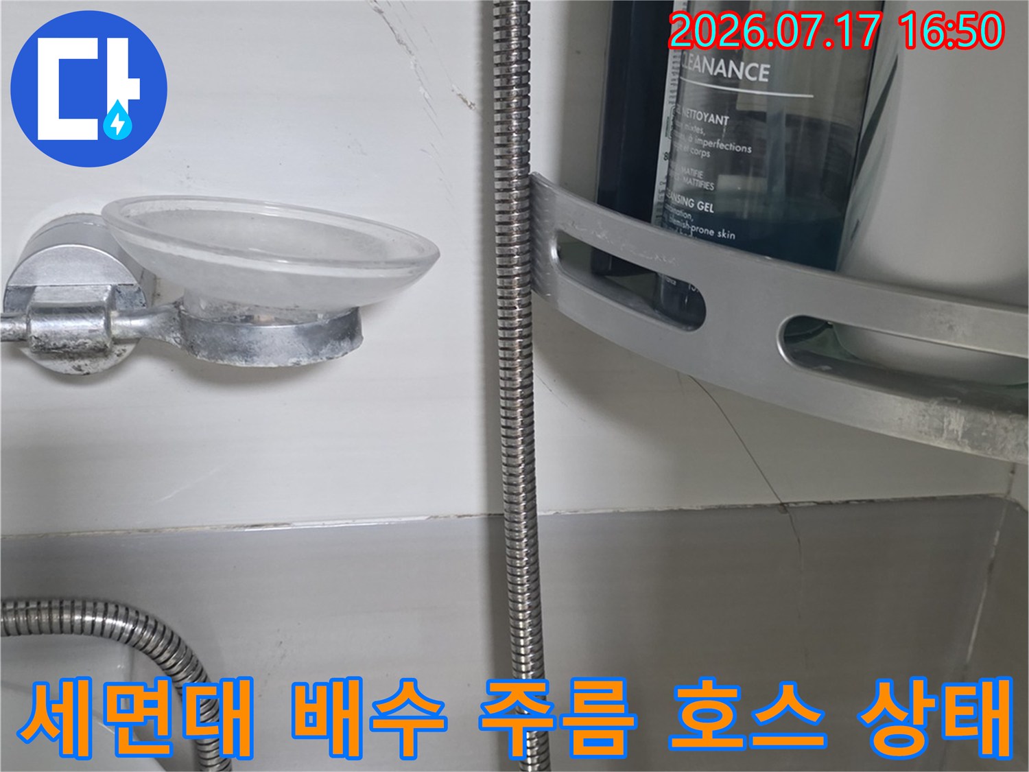 욕실 벽면에 설치된 세면대의 은색 금속제 주름 관 사진
