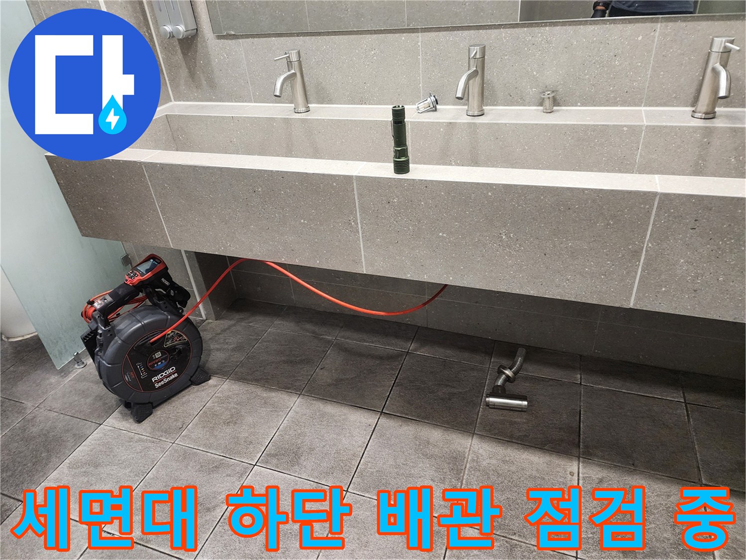 세면대 아래쪽 배수 부속과 검사용 전동 장비의 모습