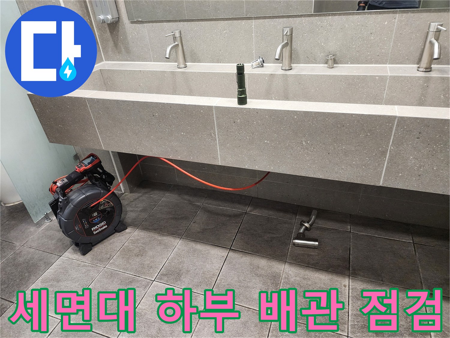 신촌 화장실 세면대 아래쪽 배관과 점검용 장비 모습