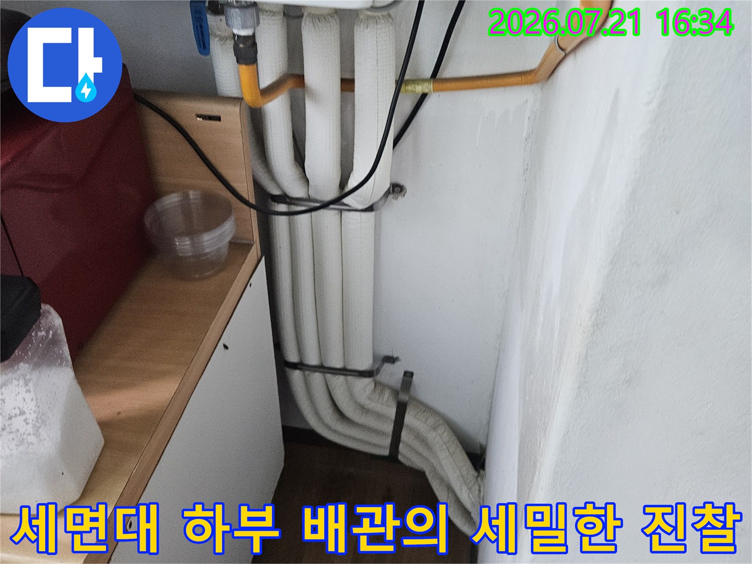 다양한 색상의 배관이 얽힌 세면대 아래 공간 점검