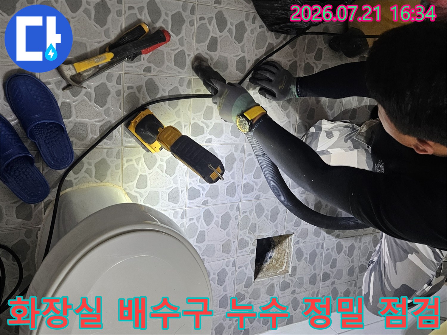 전문가용 탐지 장비를 사용하여 화장실 바닥의 배수구 주변을 세밀하게 검사하는 장면
