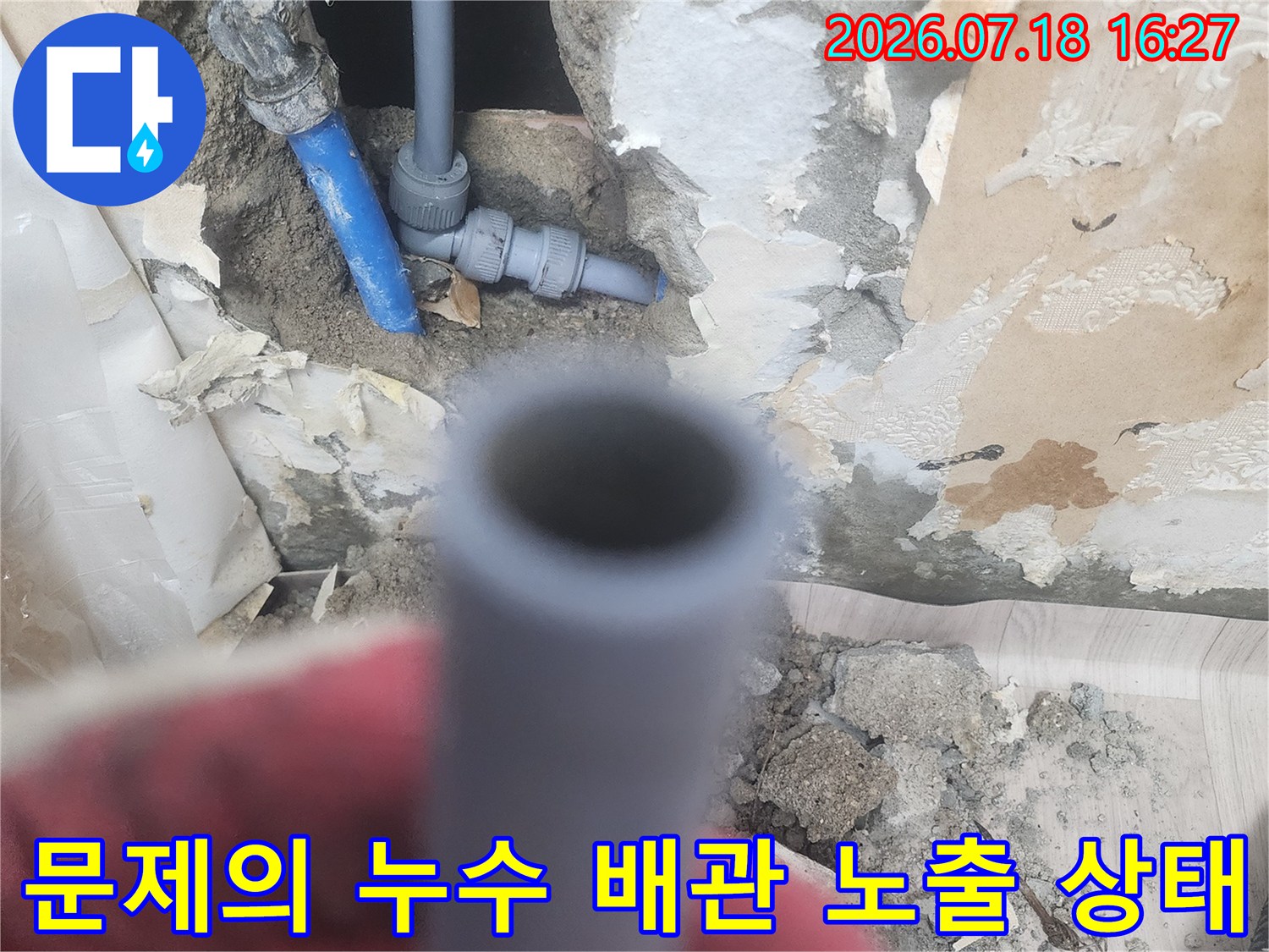 콘크리트 벽을 굴착하여 드러난 파란색 수도 배관-과 교체용 새 자재
