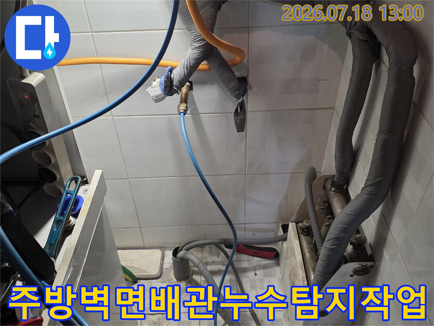 하얀색 타일 벽면에 설치된 회색 보온재 배관과 파란색 탐지 호스가 연결된 모습