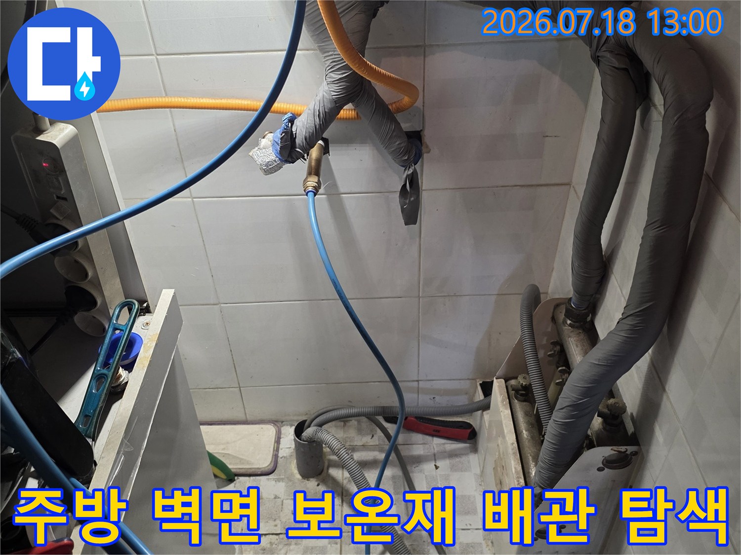회색 보온재로 감싸진 굵은 배관들과 그 아래 연결된 파란색 및 노란색 측정 호스-누수 진단 과정